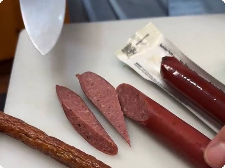 A Primal Eats brisket stick cut open next to a store-bought stick
