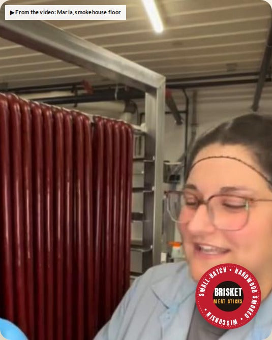 Maria on the smokehouse floor next to racks of brisket sticks