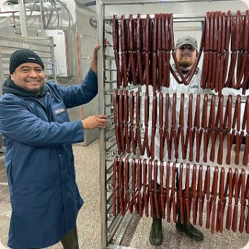 Two Primal Eats team members with a rack of brisket sticks