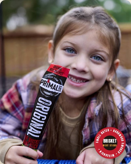 A smiling girl holding an Original brisket meat stick
